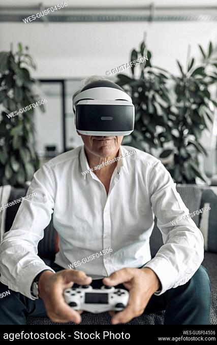 Businessman playing video game using virtual reality while sitting at office