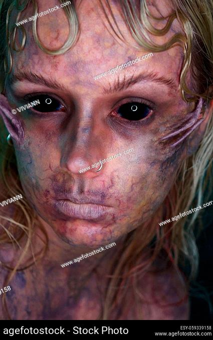 young blond woman infront of black background with scary sfx makeup