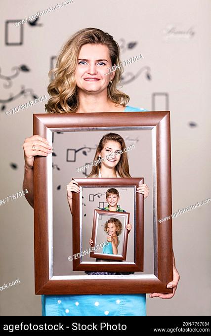 Happy mother holding portrait with her family each is located inside their own frame