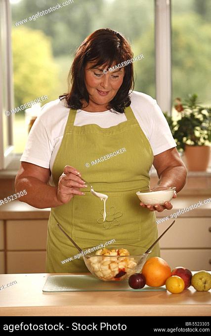 Woman prepares fruit salad with yoghurt, prepare, bowl, salad servers, spoon