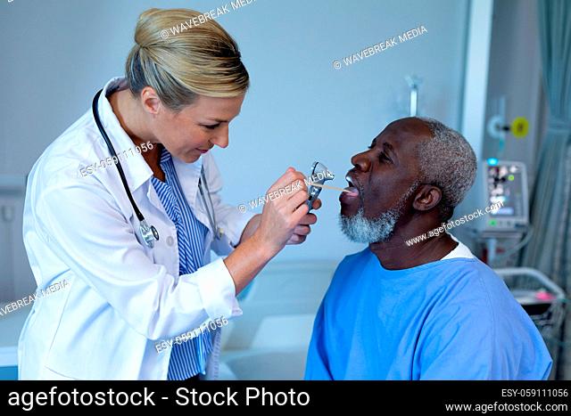 Caucasian female doctor examining throat of african american male patient in hospital room