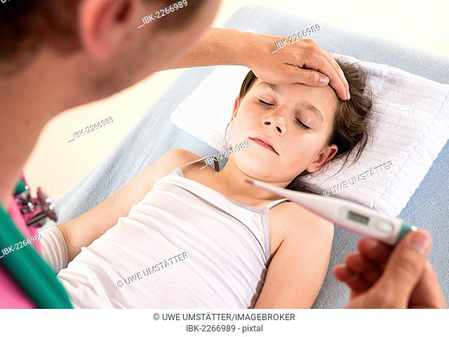 Pediatrician reading a digital fever thermometer showing the high temperature of a young girl with fever