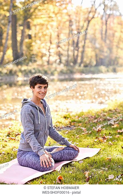 Smiling mid adult woman in forest practicing yoga, lotus position