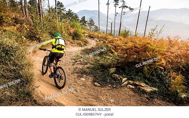 Mid adult woman cycling up dirt track, Finale Ligure, Savona, Italy