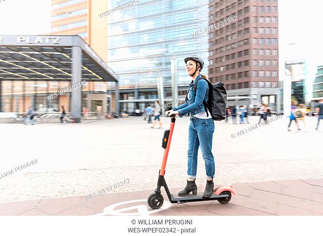 Happy woman riding e-scooter in the city, Berlin, Germany, Berlin, Germany