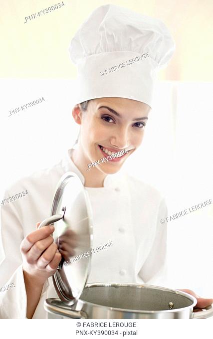 Happy female chef holding a saucepan
