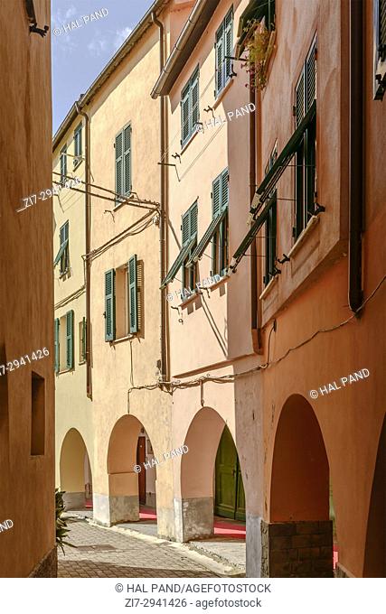 foreshortening of old picturesque bending houses with covered walkway, shot in bright late summer light at Varese Ligure, Genova, Liguria, Italy