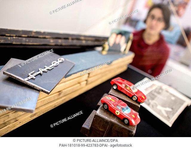 17 October 2018, Lower Saxony, Hanover: An employee looks at a lettering by the late musician Falco and two model cars in a showcase in the exhibition ""Falco