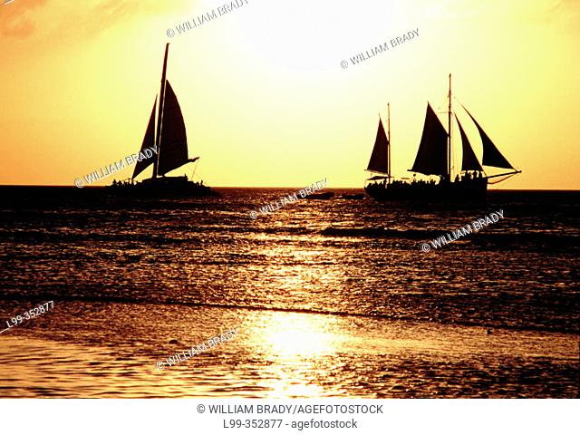 Sailboats at sunset crossing wakes in Aruba. Dutch Antilles