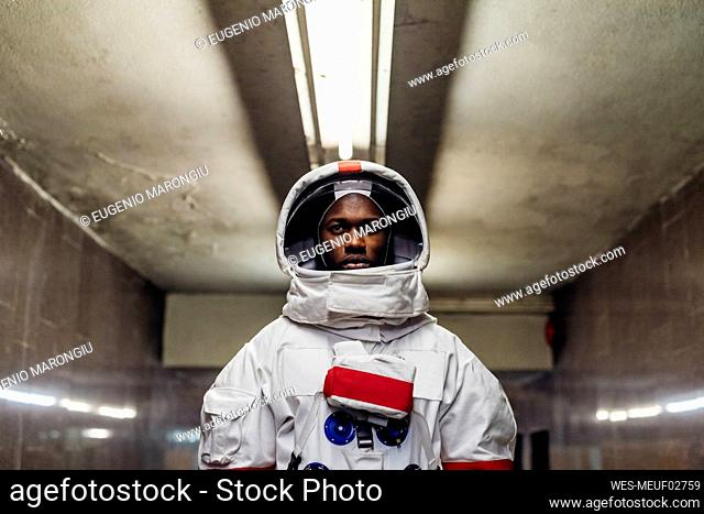 Serious man wearing space suit in basement
