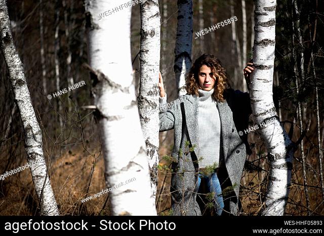 Woman standing amidst birch trees at forest