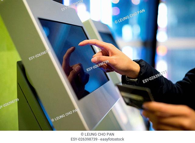 Woman using credit card on automatic ticketing machine
