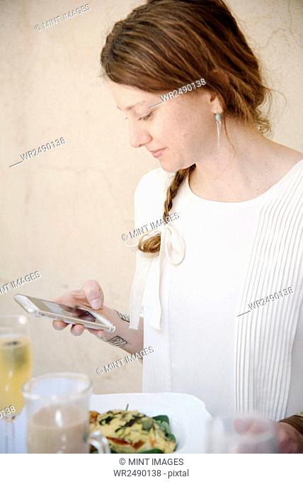 Portrait of a woman with long auburn hair in a braid, looking at her cell phone