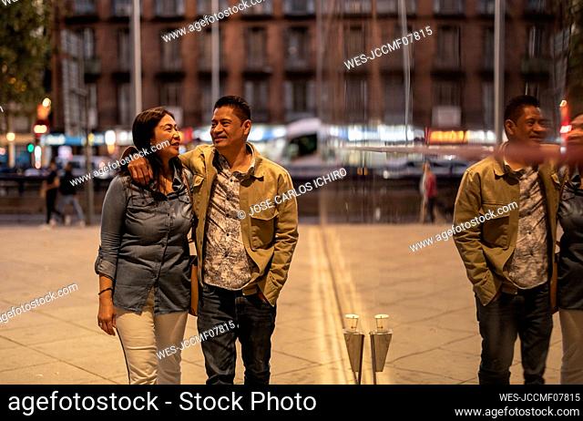 Smiling mature couple walking on footpath at night