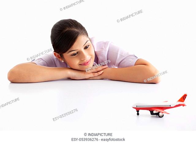 Pretty young female executive looking at model airplane