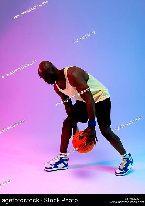 Image of african american basketball player with basketball on neon purple to blue background