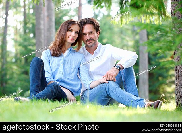 Married couple of people sitting on grass