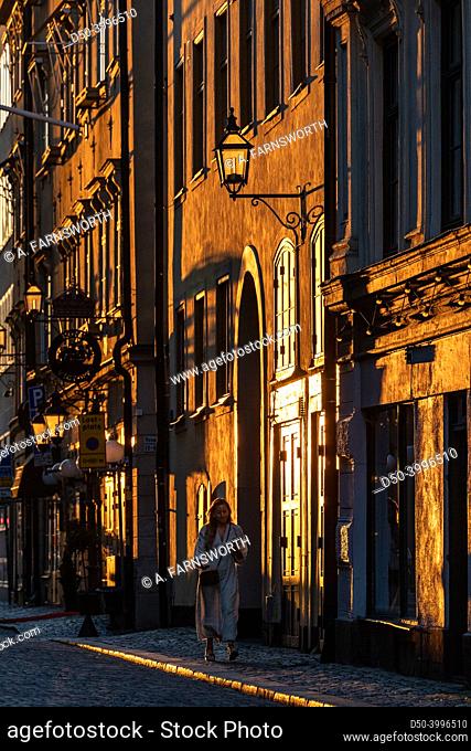 Stockholm, Sweden, A woman walks in the setting sun on lilla Nygatan on Gamla Stan or Old town