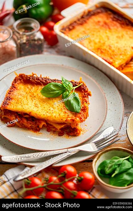 Delicious lasagne bolognese with pepper, tomato and cheese. Homemade baked dish of Italian cuisine. Flat lay ob table