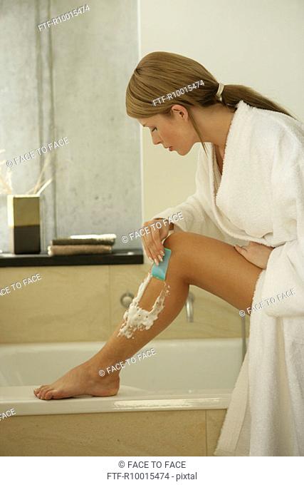 A blonde woman using an epilator on her leg