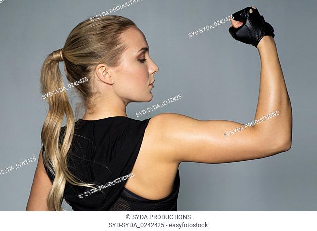 close up of woman posing and showing biceps in gym