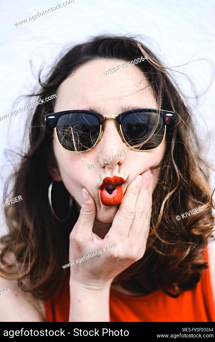 Portrait of young woman with red lips wearing sunglasses pouting mouth