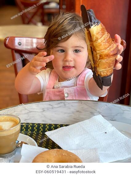 Girl picks up croissant with great appetite and eagerness