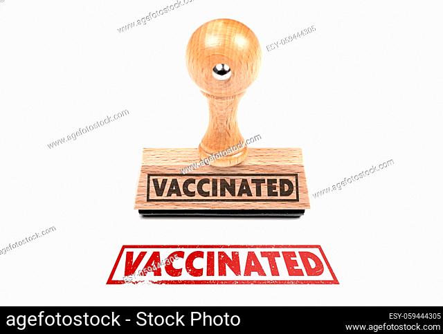 wooden rubber stamp and imprint with text VACCINATED on white background
