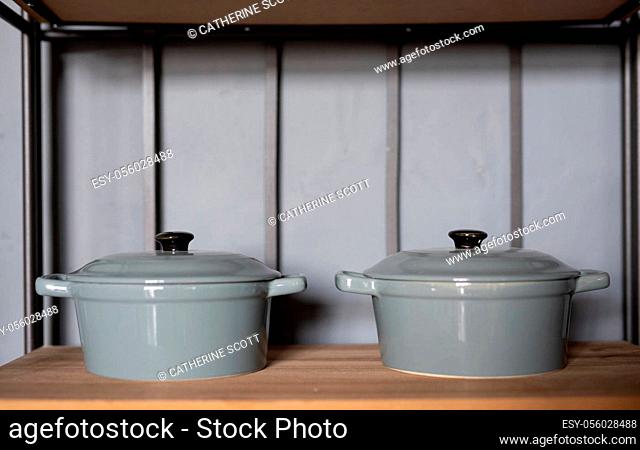 Two grey casserole dishes on a shelf in a kitchen