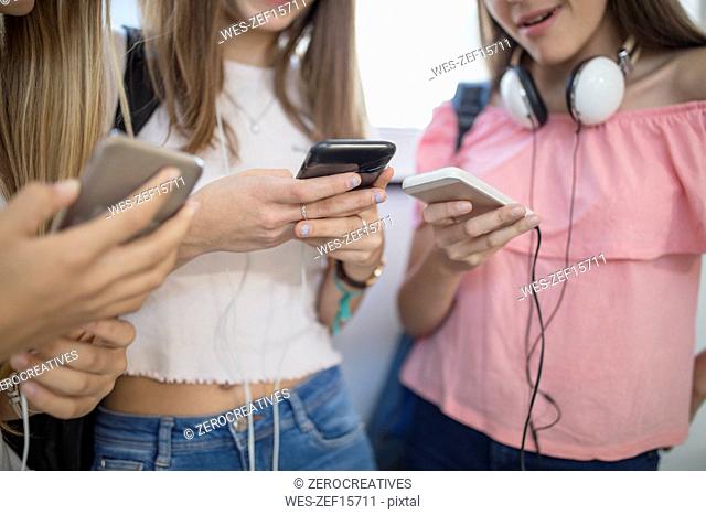 Teenage girls using cell phones in school
