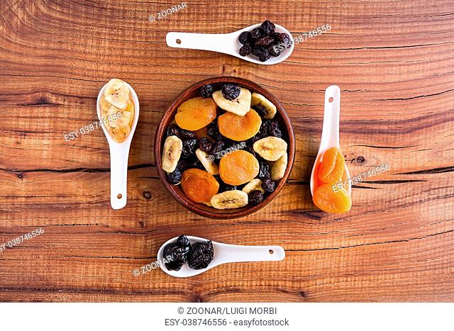 Mix of dried fruits in a wooden bowl over a rustic table