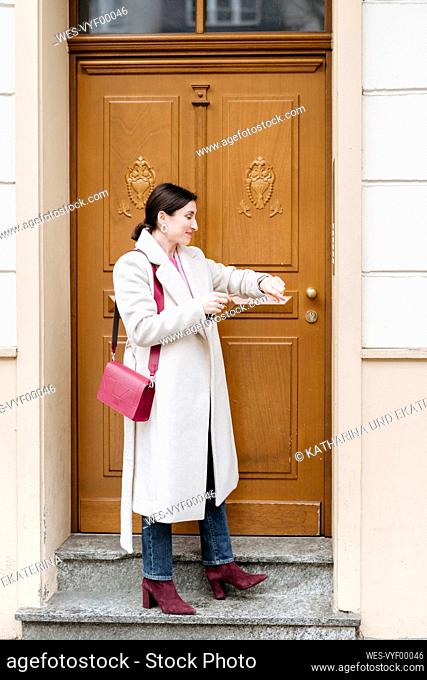 Smiling woman looking at her watch near the door