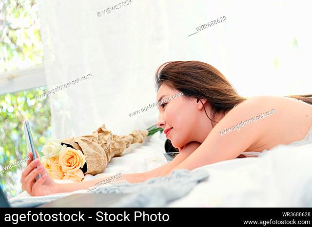 Lying on the bed with mobile phone autodyne beautiful young women