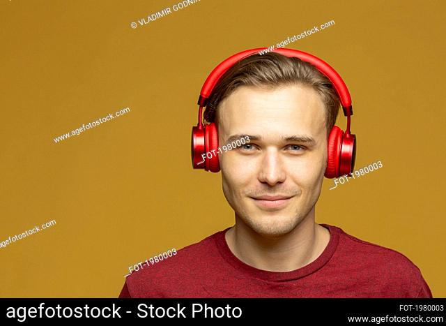Studio portrait confident young man listening to music with headphones