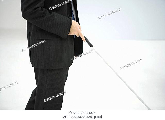 Businessman walking with white cane, cropped view