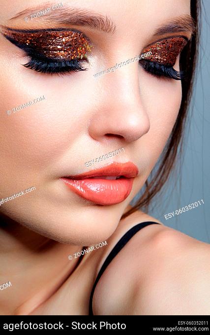 Close-up shot of female face with vogue golden shining eyes makeup. Eyes closed