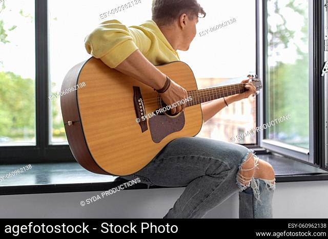 close up of man playing guitar sitting on sill