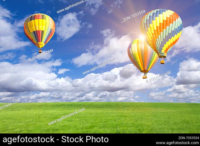 Two Hot Air Balloons Up In The Beautiful Blue Sky With Grass Field Below