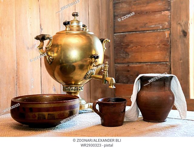 Old samovar and ceramic dishes on a table in a country house