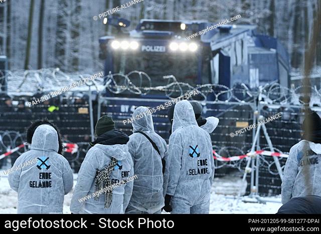 05 December 2020, Hessen, Dannenrod: Activists stand in front of a police water cannon. In Dannenröder Forst, opponents of expansion have again erected...