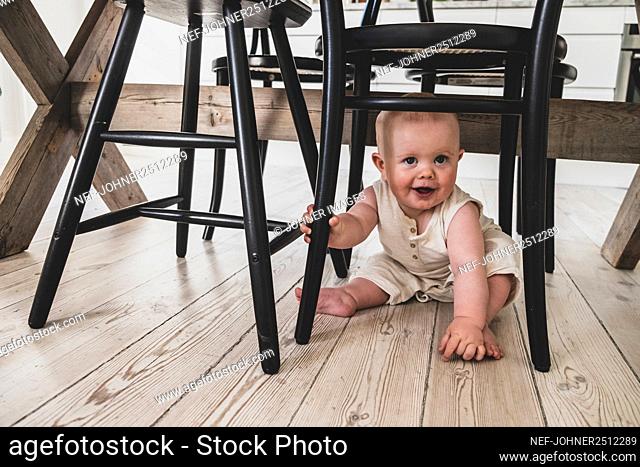 Smiling baby sitting under chair