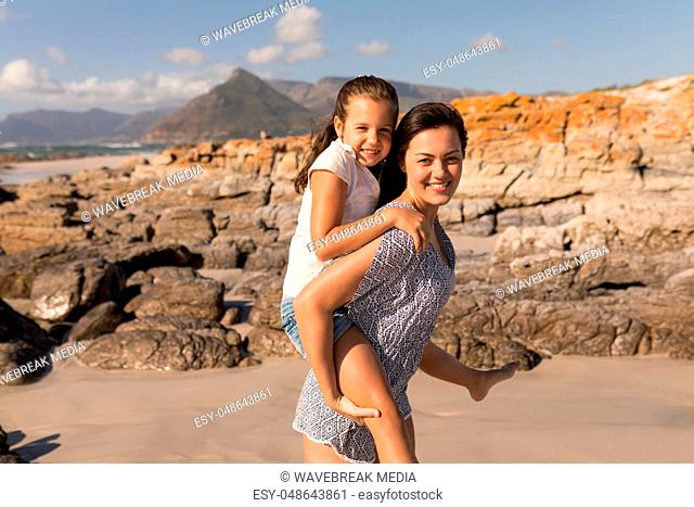Beautiful young mother giving piggyback to her daughter