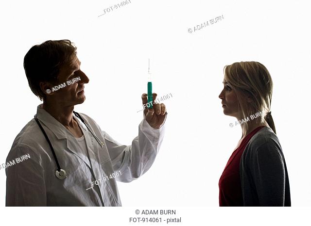 A doctor holding up a syringe facing a worried patient