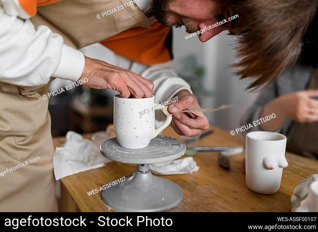 Male expert polishing cup with sand paper at workshop