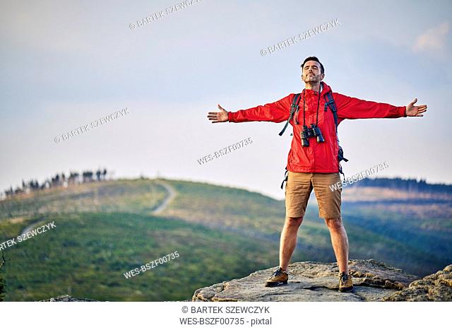 Man standing with outstretched arms on mountain top