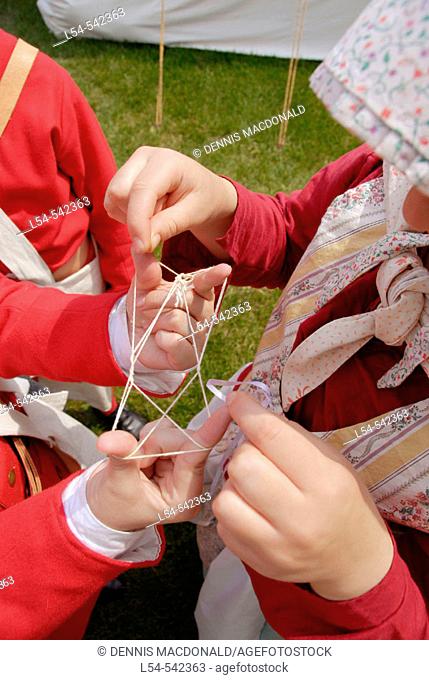 Children play a historical version of a string game. Circa 1700 reenactment of the Colonial period lifestyle in Southeastern Michigan at the Feast of Sainte...