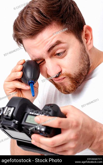 young photographer cleaning camera with vacuum pump. hand blower dust cleaner for camera and lenses. soft light
