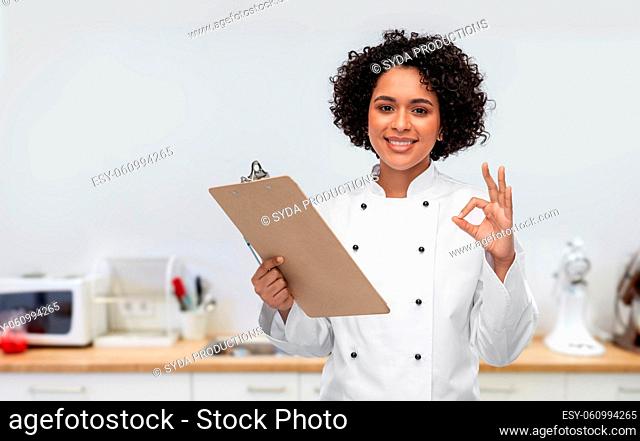 smiling female chef with clipboard on kitchen