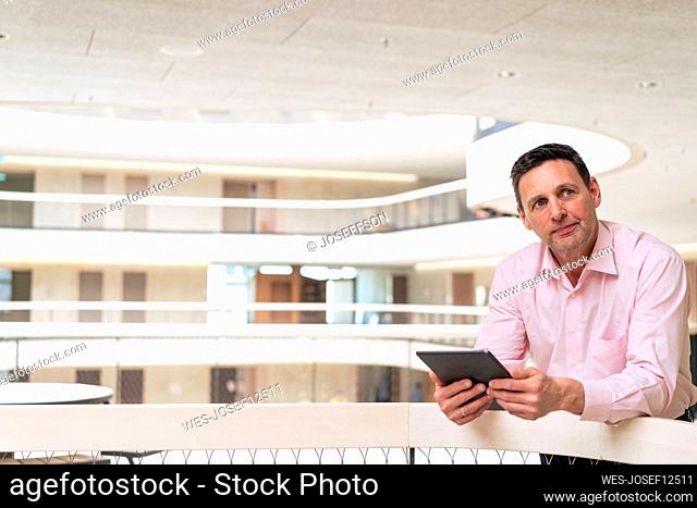 Thoughtful businessman with tablet PC in corridor