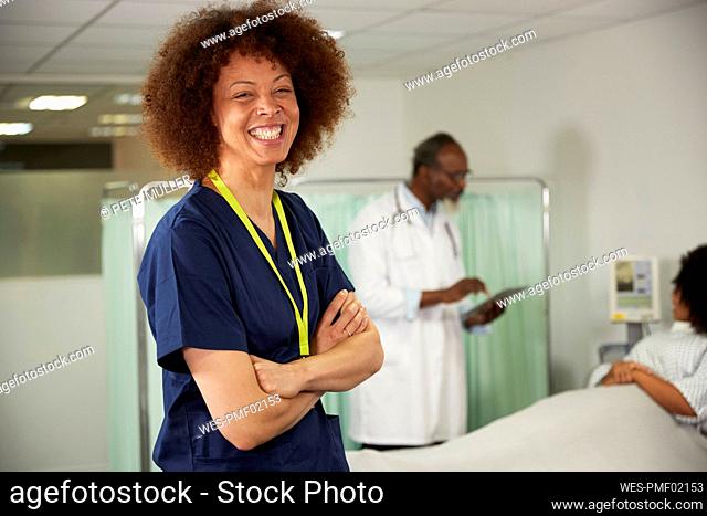 Happy female nurse with arms crossed in medical room